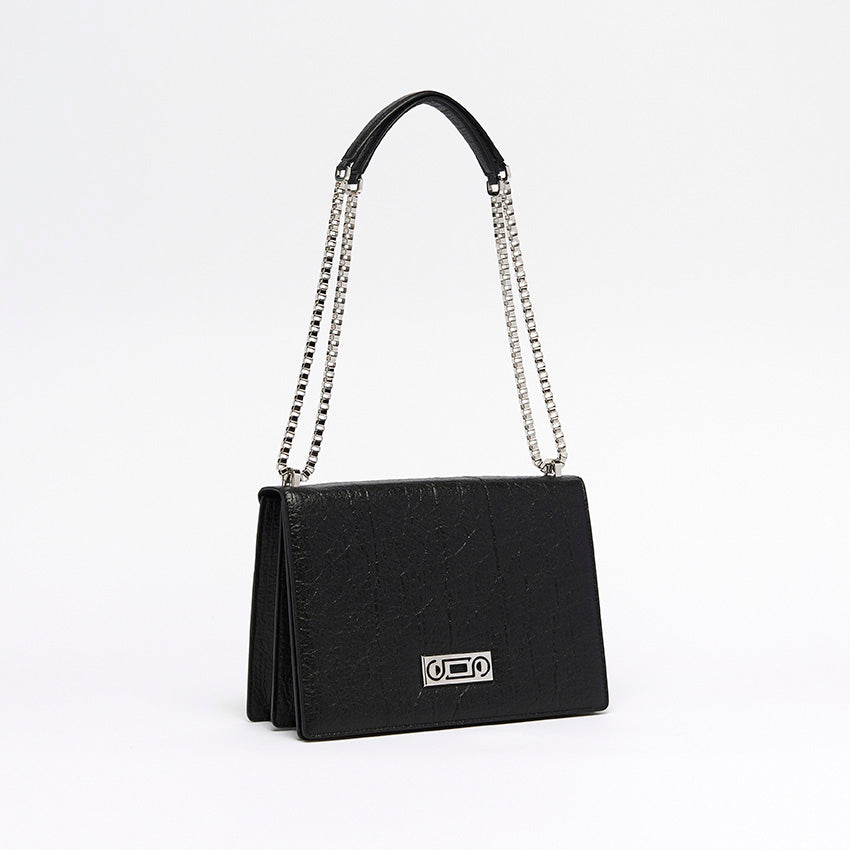 The Cristiana Vegan Shoulder Bag by Studio Tondini. Three-quarter view of the black version, highlighting the radiant chain plated in real palladium and the sculptural structure crafted from Piñatex®.